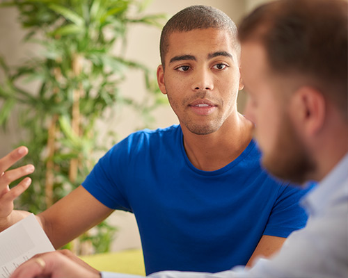 a male university student is having a one to one with his college lecturer or counsellor